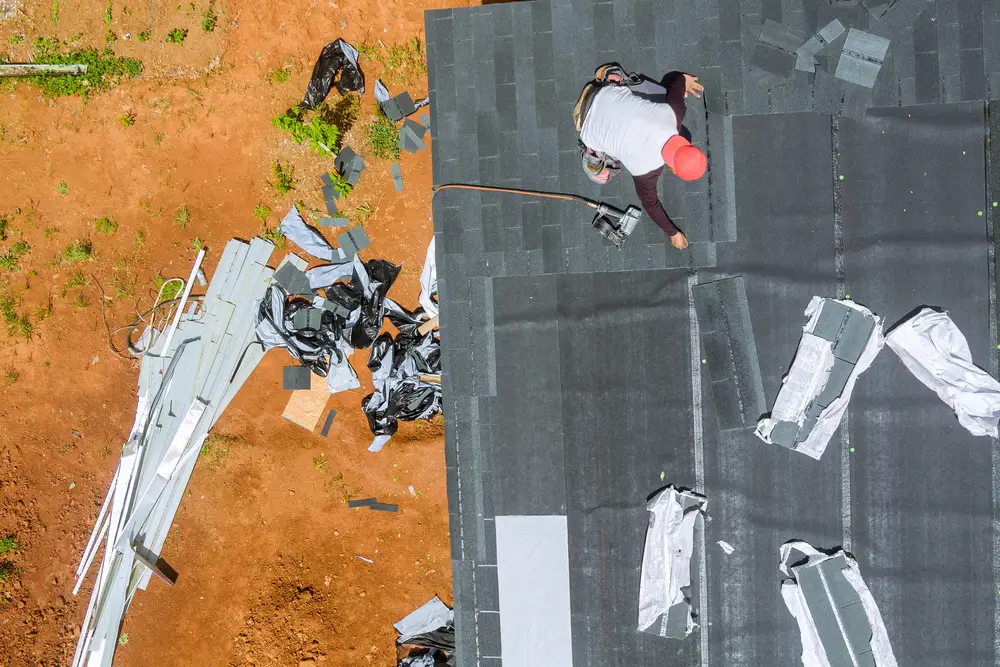 Roofer replacing asphalt shingles on a home