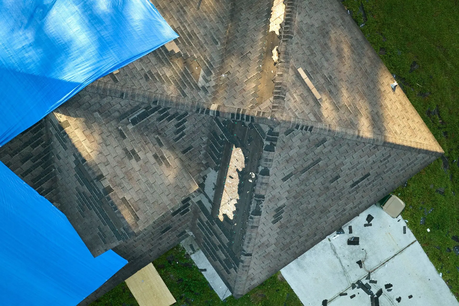 Storm-damaged shingle roof with a blue tarp