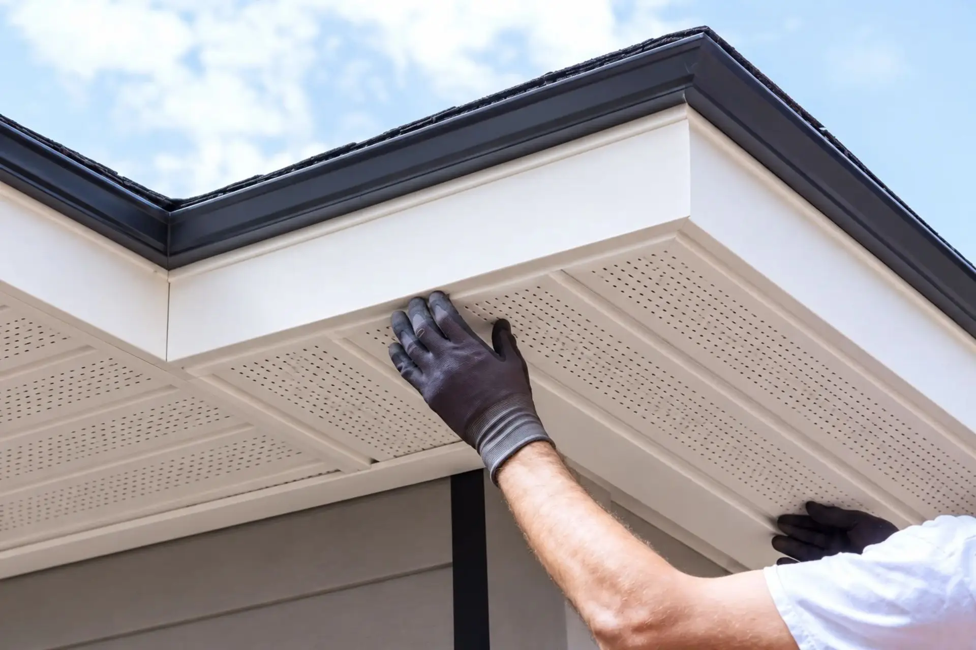Worker fitting fascia trim under a roof edge