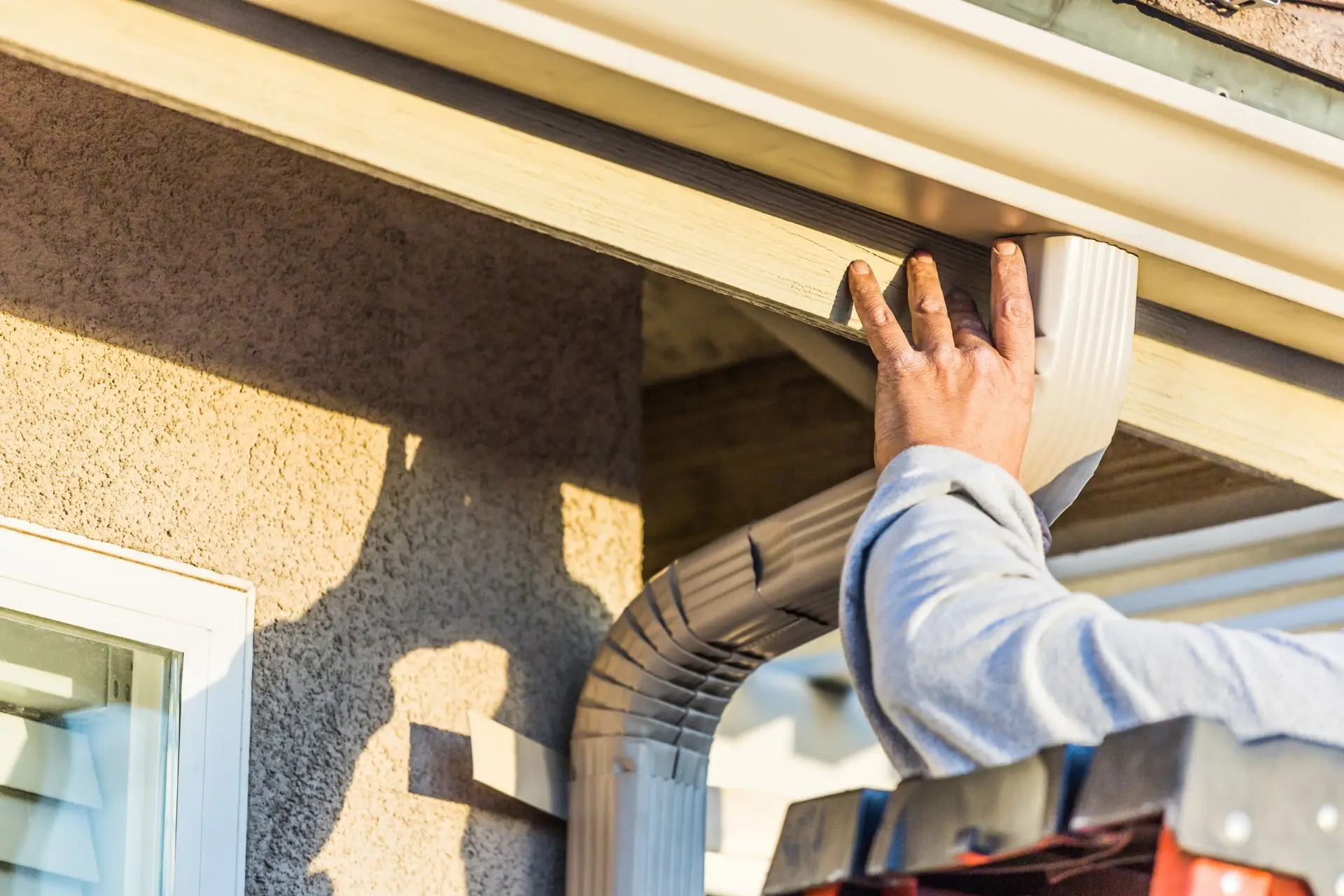 Worker installing a gutter on a house