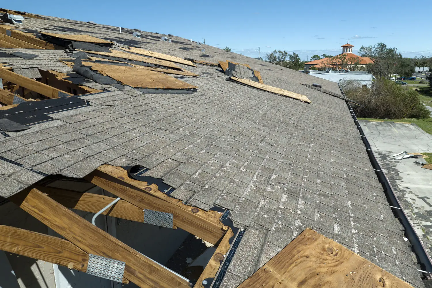 Storm-damaged roof with missing shingles and exposed decking