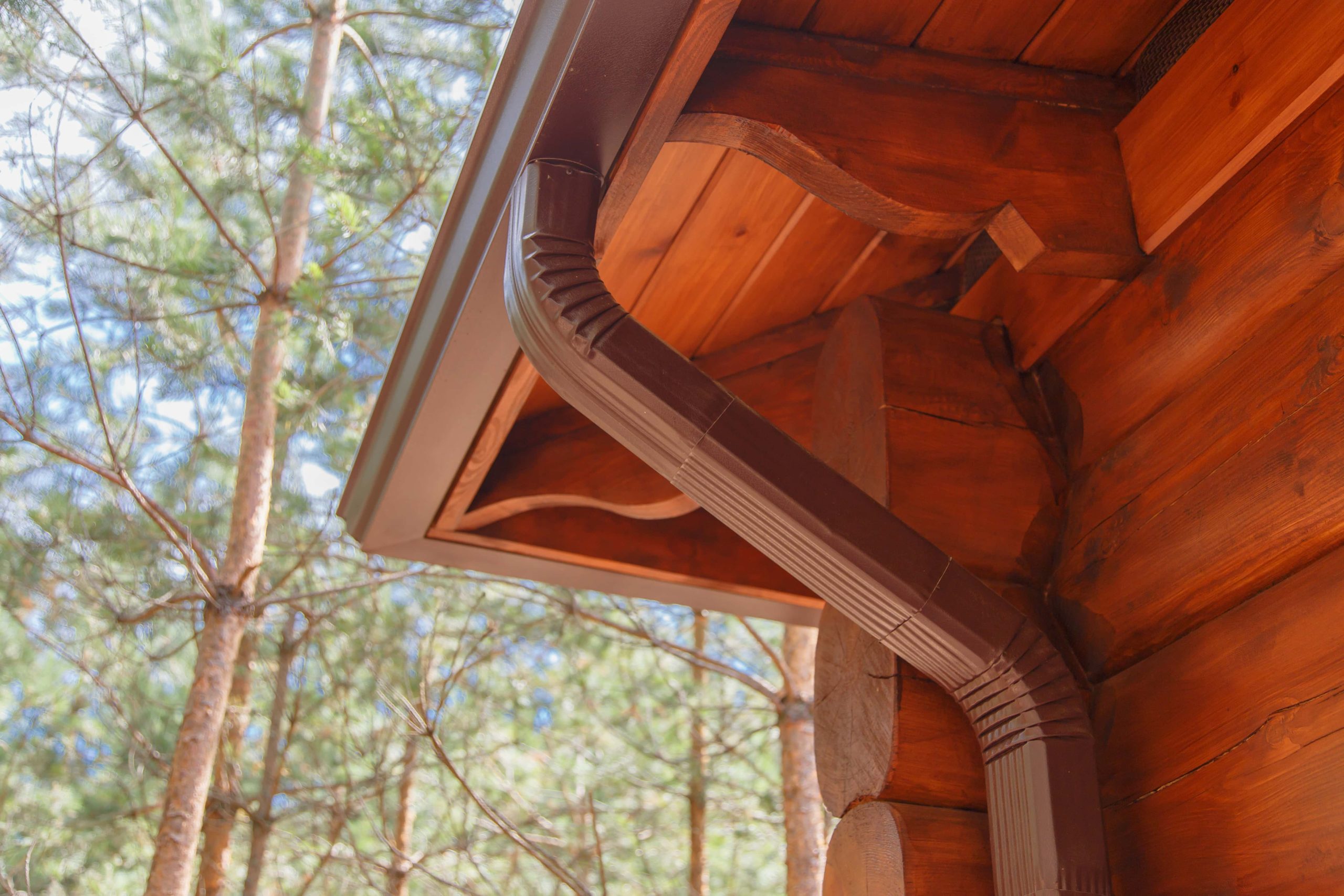 Copper-colored gutter and downspout on a wooden house