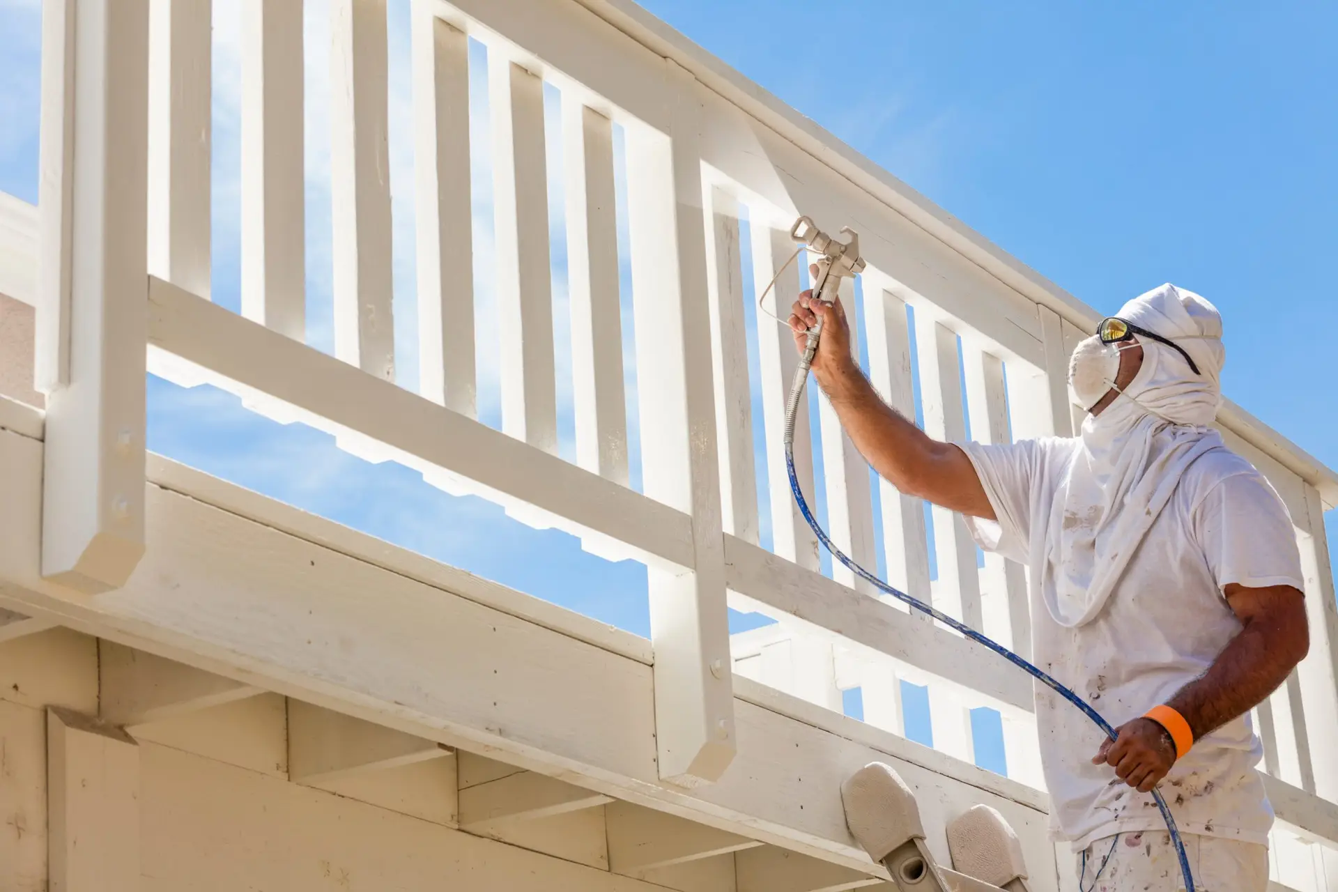 Painter spray-painting a wooden railing