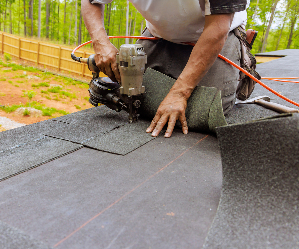 Roofer nailing asphalt shingles with a nail gun